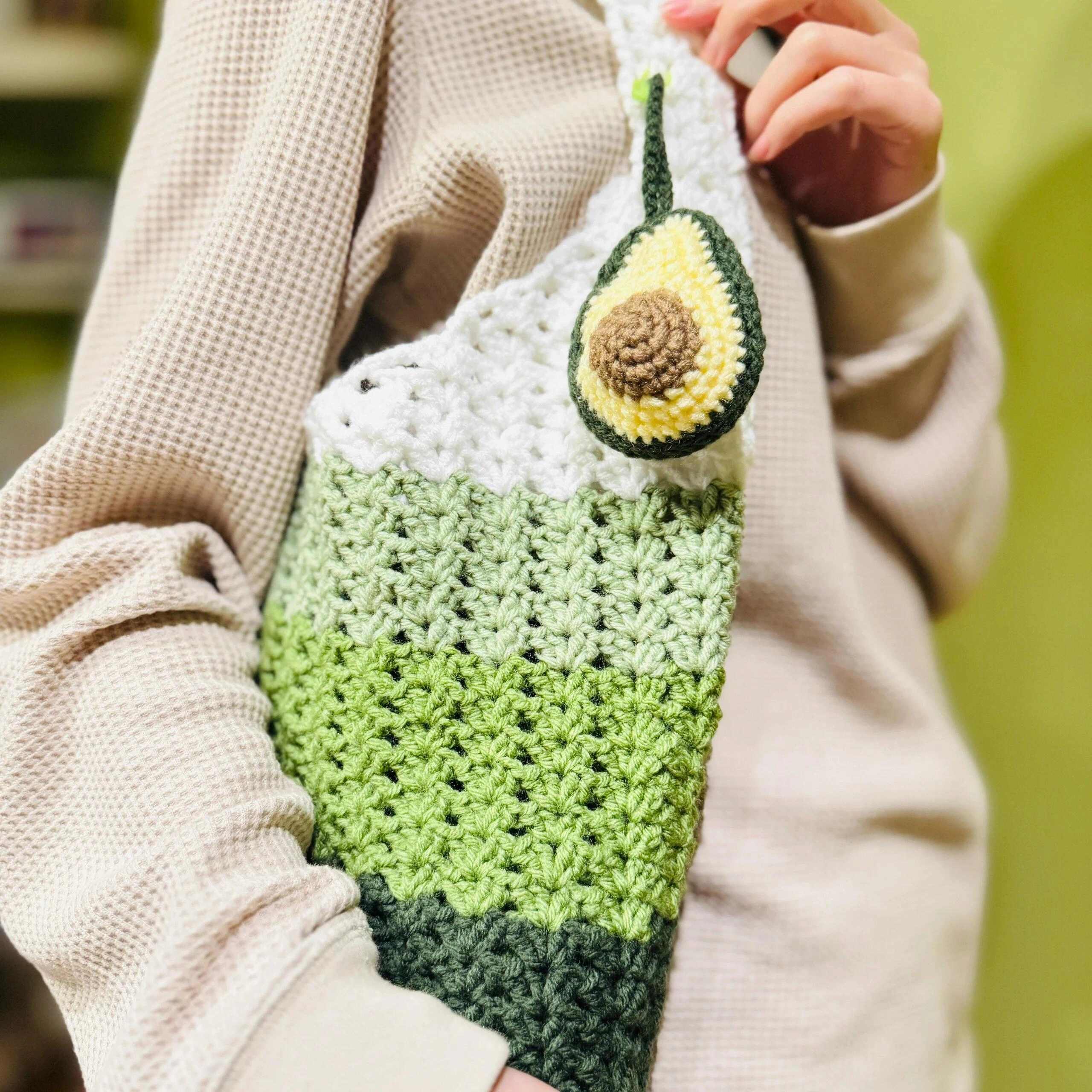 Finished green crochet avocado shoulder bag worn with beige knitwear