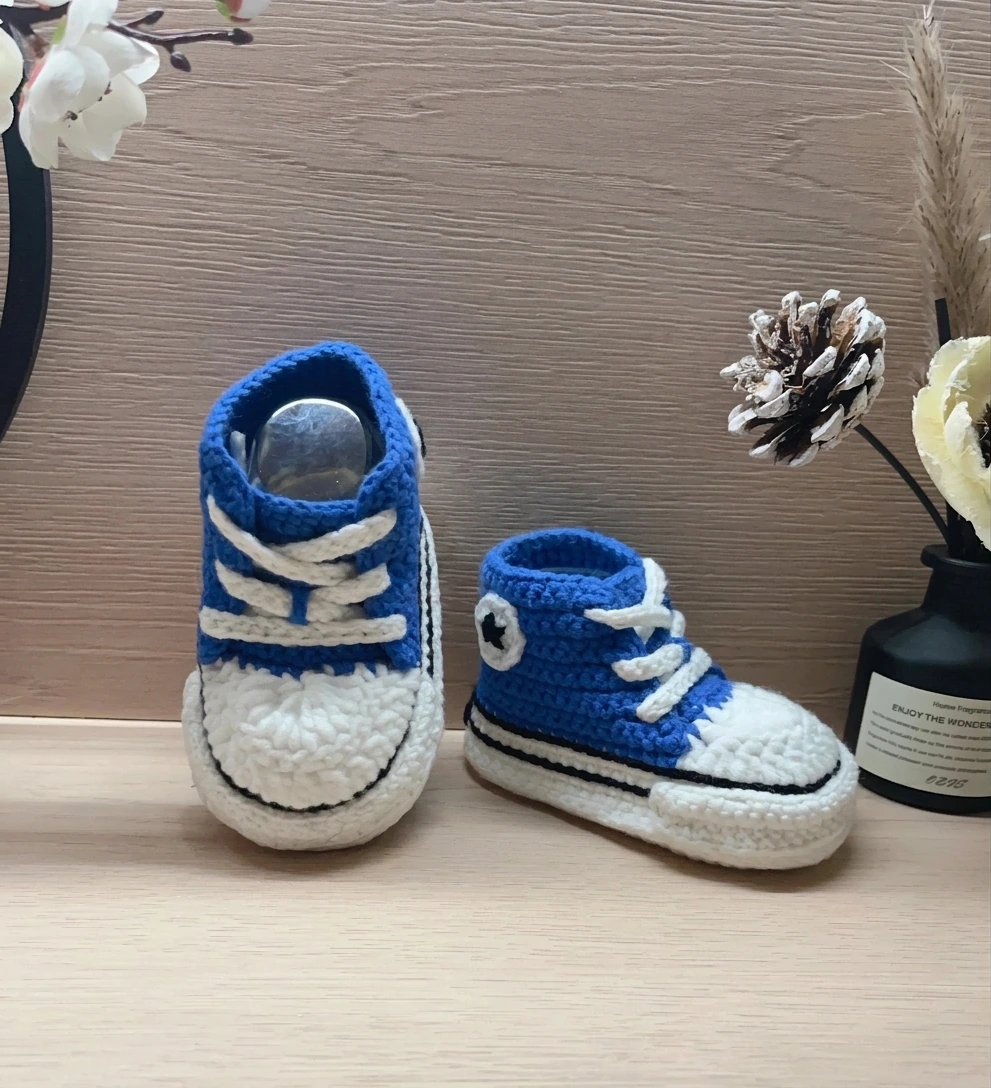 Blue crochet baby sneakers with white laces, toe caps and circular ankle patches
