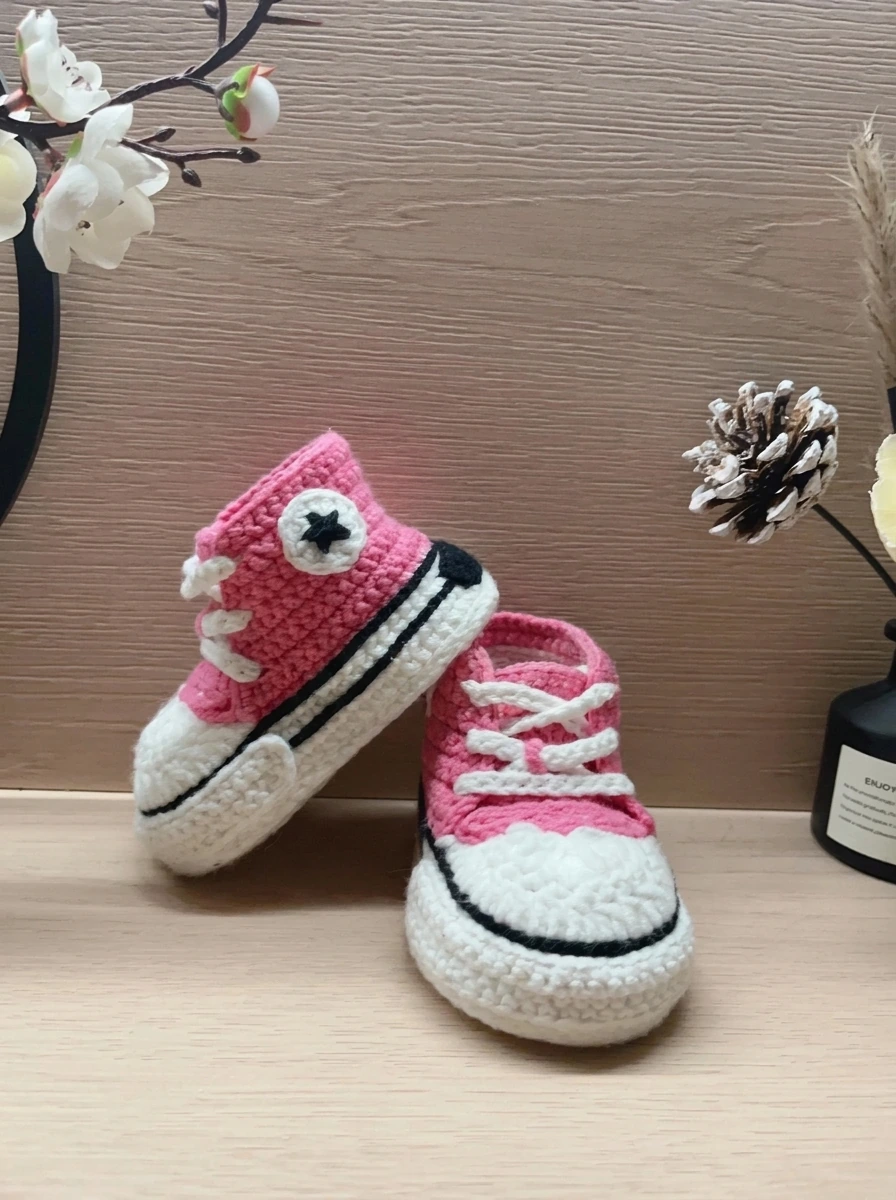 Pink high-top crochet baby sneakers showing the white star patch and lace-up front