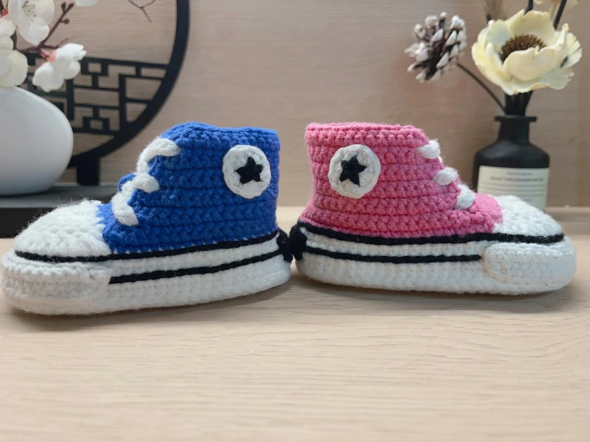 Side view of blue and pink crochet baby sneakers with black sole edging