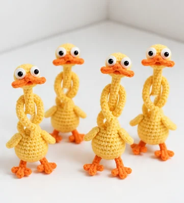 Four assembled yellow crochet ducks showing their long necks and orange feet