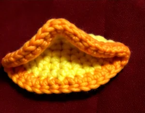 Yellow crochet duck face base edged with orange yarn