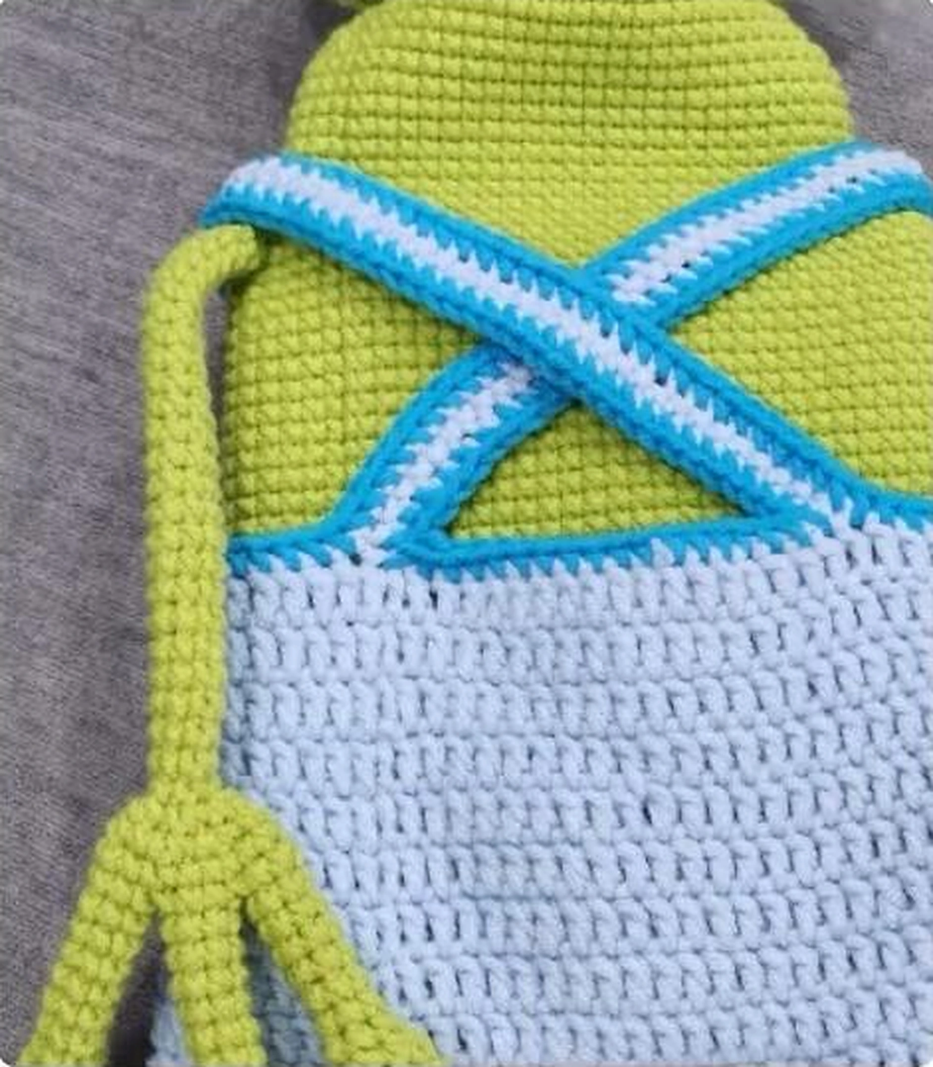Crossed light blue crochet overall straps with turquoise edging on the frog back