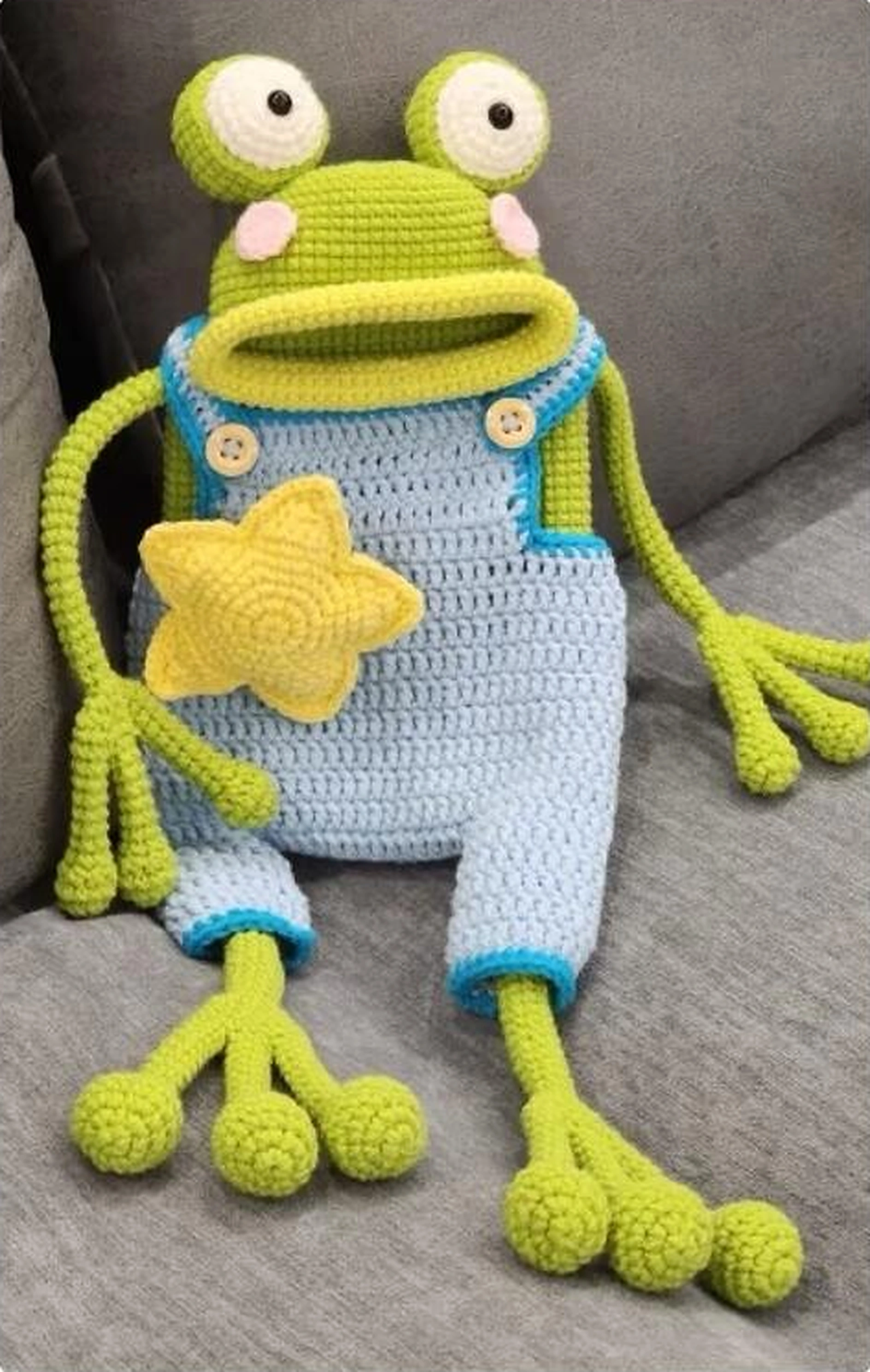 Crochet frog bag in blue overalls with raised eyes, a wide mouth and a yellow star