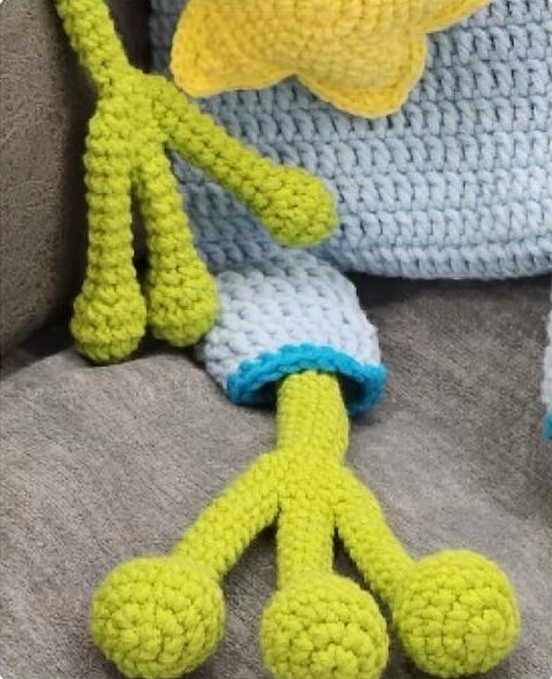 Rounded crochet frog fingers and toes beside a blue overall cuff
