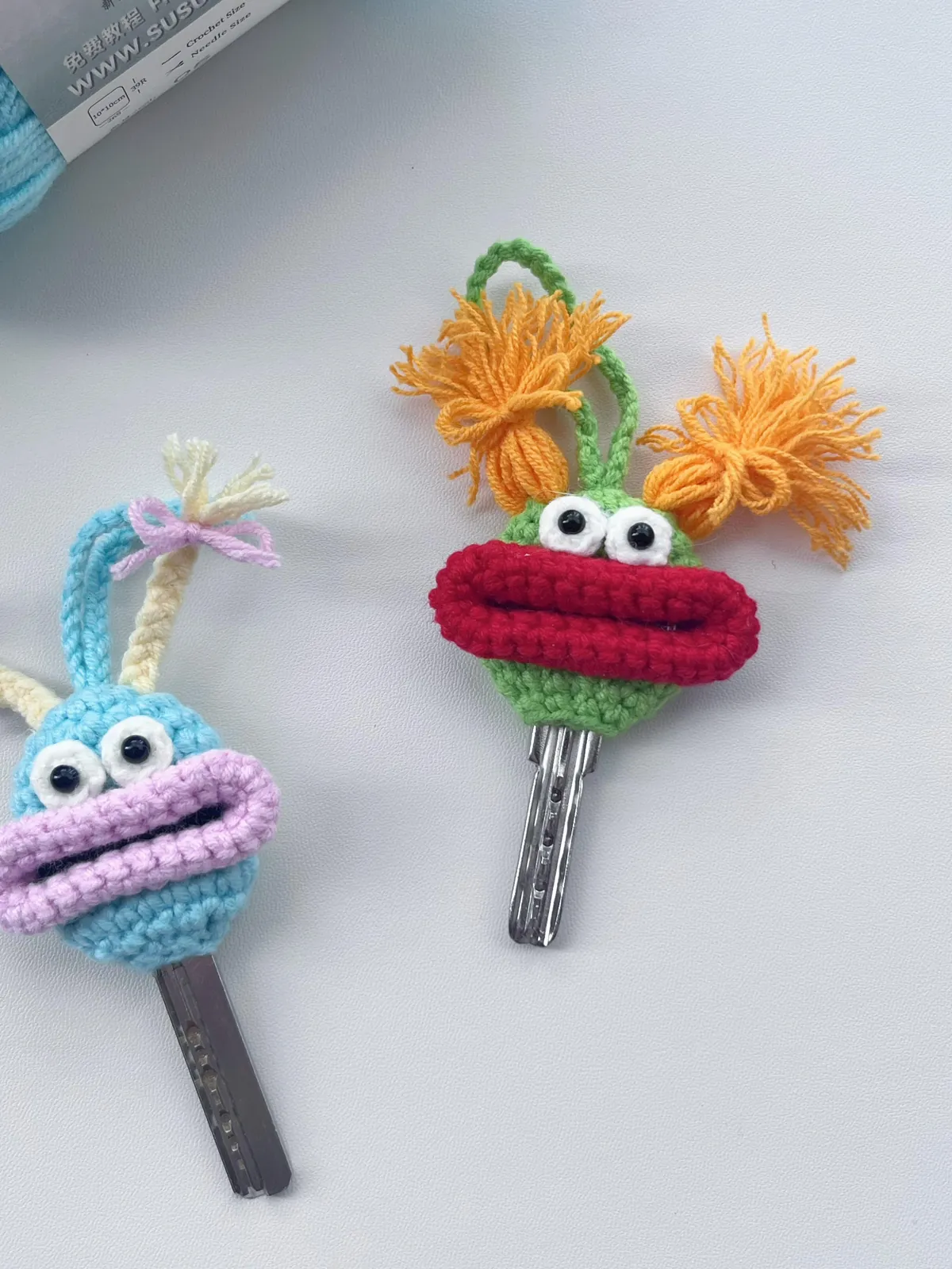 Green crochet monster key cover with red lips and orange yarn hair