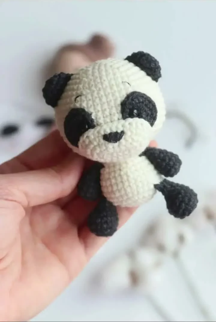 Panda keychain crochet pattern reference showing a white panda with black ears, eye patches and limbs