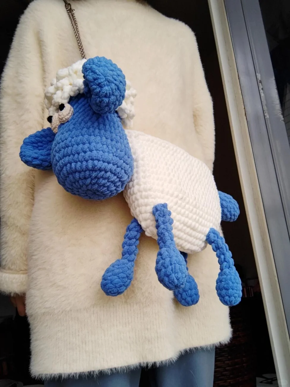 Side view of a blue and white sheep shoulder bag with four dangling legs