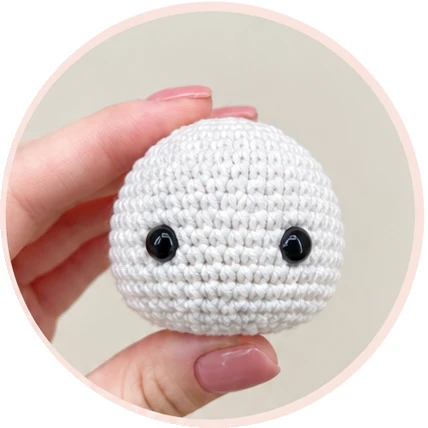 White crochet snowman head with black eyes before facial finishing