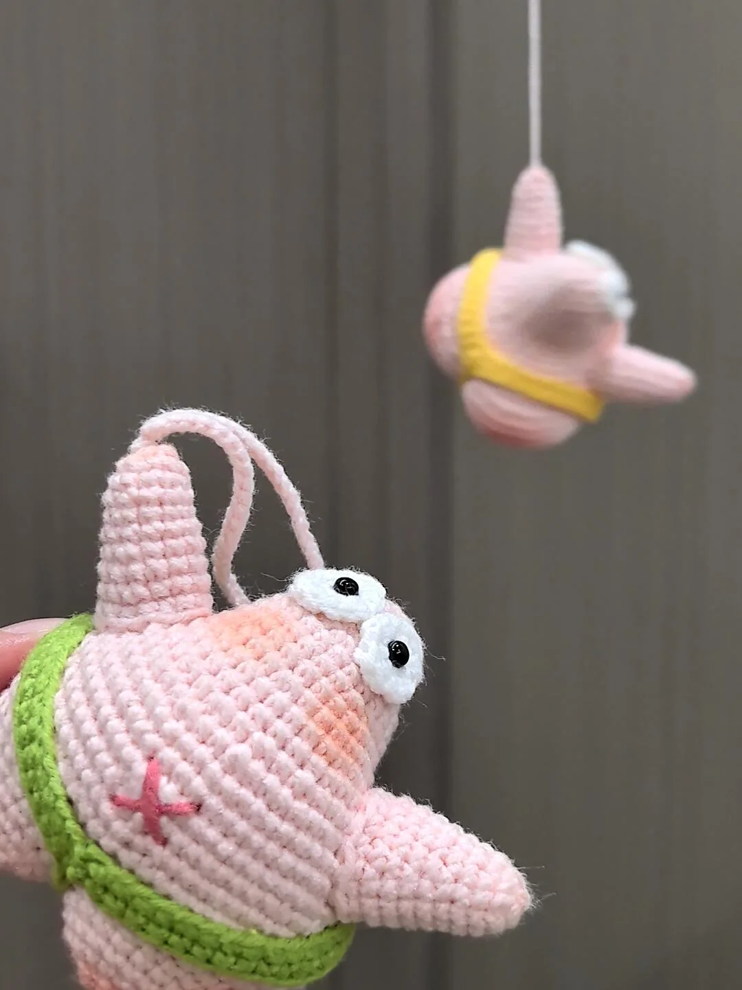 Real crochet starfish charm close-up with white eyes, pink embroidery and green waistband