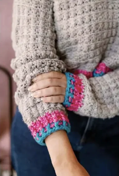 Original photo of pink and turquoise crochet cuff bands on gray sleeves