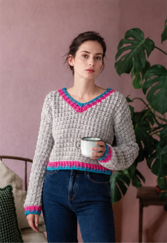 Original front view of a pearl-gray cropped V-neck crochet sweater with pink and blue trim