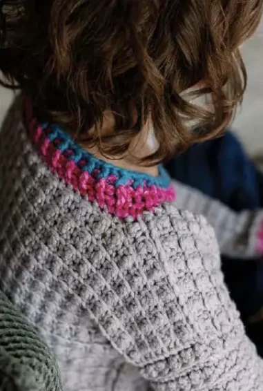 Original close-up of gray crochet texture and pink and blue neckline ribbing