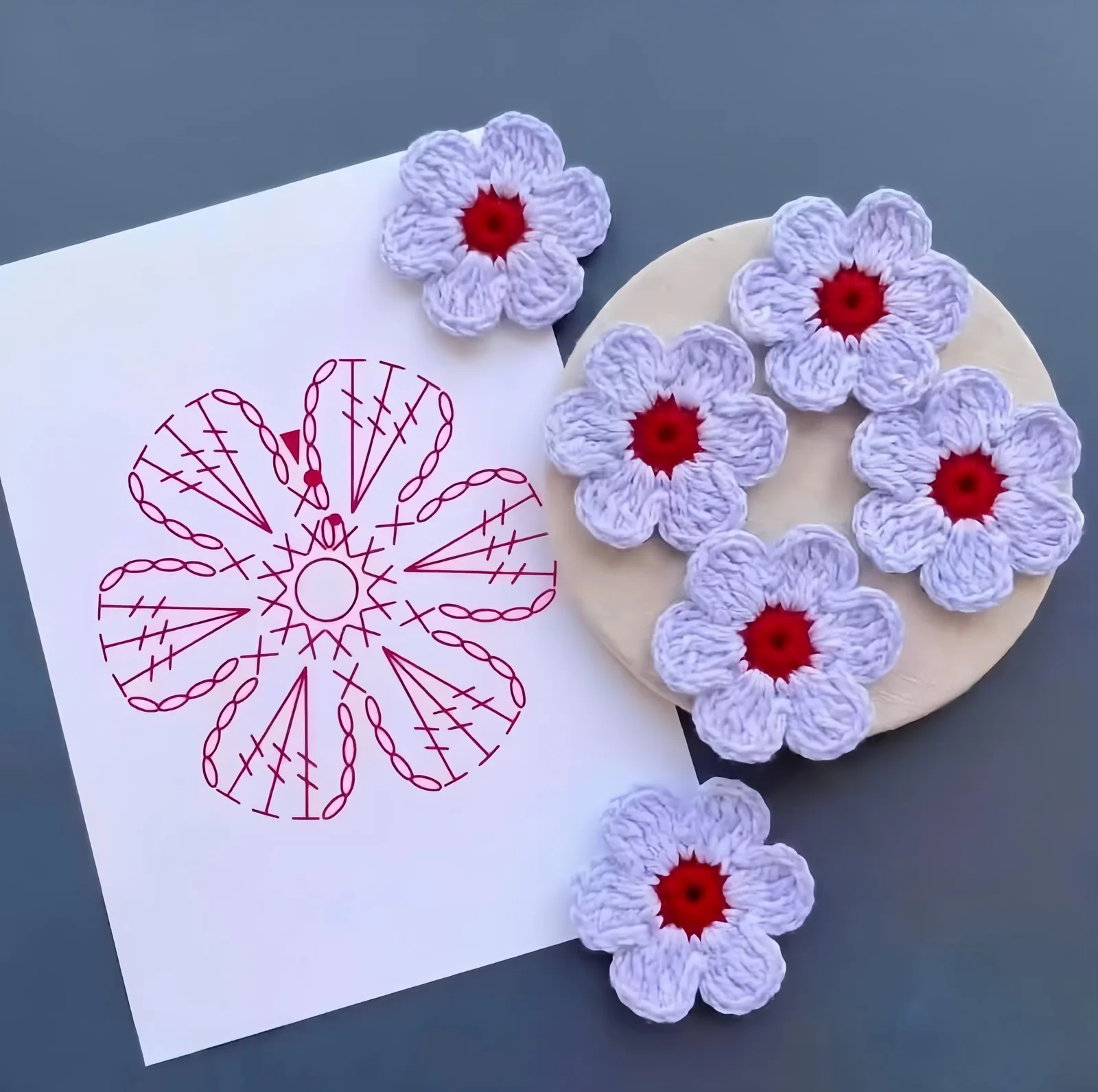 White five-petal crochet flower patterns with red centers and symbol chart